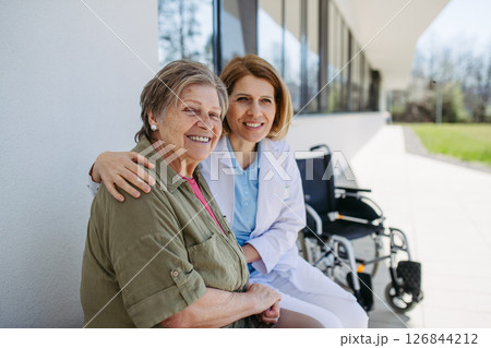 Elderly patient talking with caring female physician in front of hospital. 126844212
