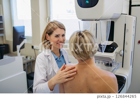 Healthcare professional adjusts the patient for accurate breast imaging. 126844265