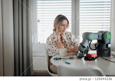 Woman engineer working on robotic arm project at home. Woman engineer working on robotic arm project at home. 126844286
