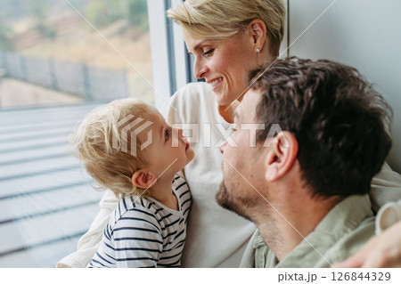 Parents playing with little son, sitting by window. Parents playing with little son, sitting by window. 126844329