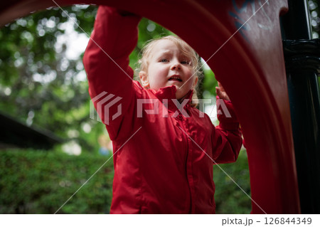 Child in red coat resting at play area. 126844349