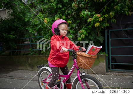 Little girl riding pink bike with basket, wearing helmet. Little girl riding pink bike with basket, wearing helmet. 126844360
