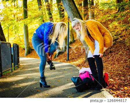 Two women changing shoes in autumn park 126844817