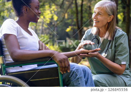 Nurse doing rehabilitation exercises with an african american female patient in the park 126845556