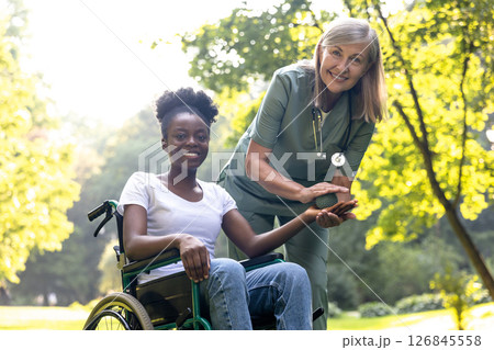 Nurse doing rehabilitation exercises with an african american female patient in the park Nurse doing rehabilitation exercises with an african american female patient in the park 126845558