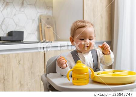 Sweet caucasian baby boy making breakfast while sitting on his chair Sweet caucasian baby boy making breakfast while sitting on his chair 126845747