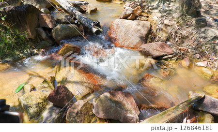 Clear Stream Flowing Over Colorful Rocks in Tropical Forest 126846181