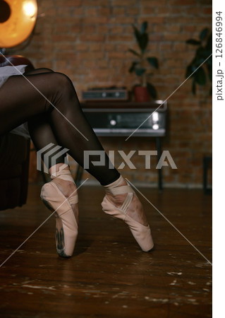 A ballet dancer in pink pointe shoes is relaxing comfortably at home, enjoying the ambiance A ballet dancer in pink pointe shoes is relaxing comfortably at home, enjoying the ambiance 126846994