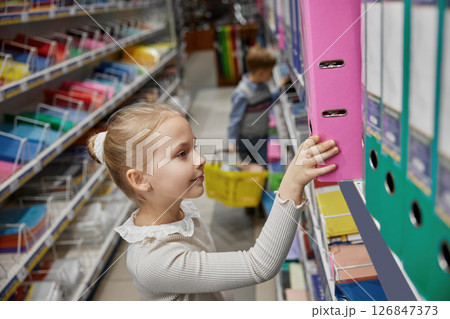 Little schoolgirl selecting paper document archive folder in stationery store 126847373