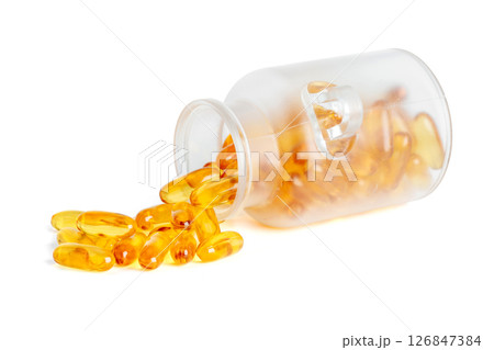 Frosted glass jar tipped over with golden fish oil softgel capsules spilling out isolated on white background 126847384