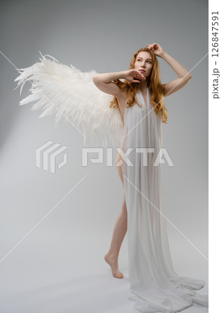 Red nude woman with angel wings posing elegantly in a modern studio setting Red nude woman with angel wings posing elegantly in a modern studio setting 126847591
