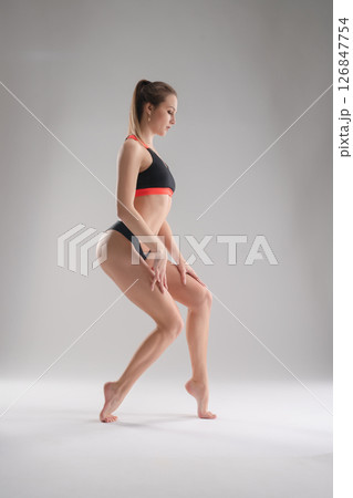 Woman posing in a sporty outfit for a studio photoshoot showcasing athleticism Woman posing in a sporty outfit for a studio photoshoot showcasing athleticism 126847754