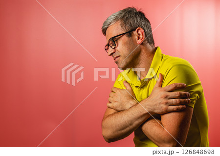 Man in yellow shirt showing discomfort against pink background Man in yellow shirt showing discomfort against pink background 126848698