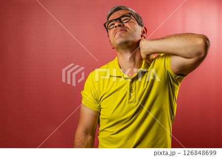 Man in yellow shirt experiences discomfort in neck 126848699