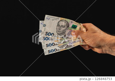 Hand holding multiple banknotes against a dark background Hand holding multiple banknotes against a dark background 126848753
