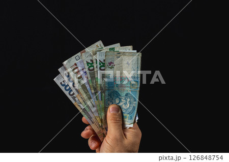 Hand holding various banknotes with a dark background 126848754