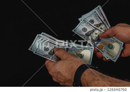 Hands counting hundred dollar bills in low light 126848760