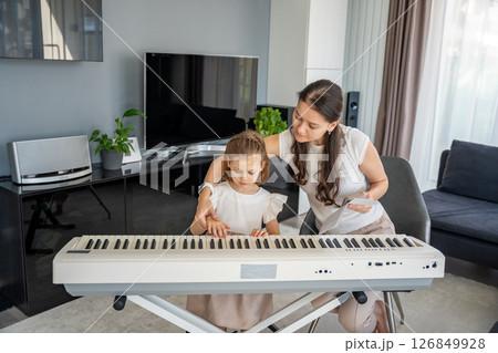 Individual piano lesson for a young child at home in the living room. Concept of early childhood development through personalized music education. 126849928