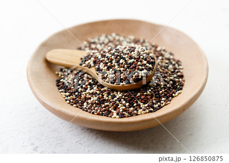Mix of white, black and red quinoa seeds in wooden spoon. Mix of white, black and red quinoa seeds in wooden spoon. 126850875