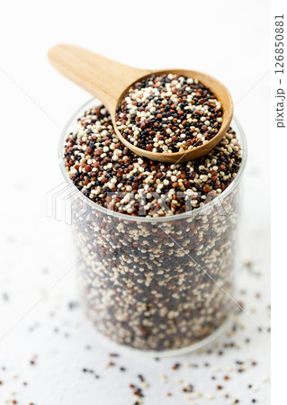 Mix of white, black and red quinoa seeds in wooden spoon. 126850881