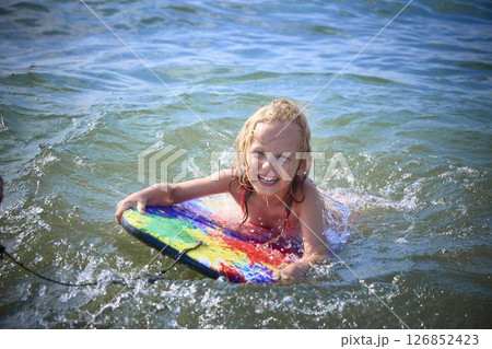 Child Smiling While Riding a Boogie Board in the Sea Child Smiling While Riding a Boogie Board in the Sea 126852423