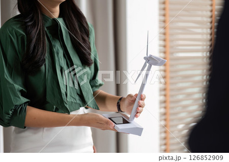 ESG Focus on Renewable Energy. Woman presenting wind turbine model in a corporate setting. 126852909