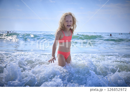 Child Joyfully Playing in Shallow Ocean Waves at the Beach 126852972