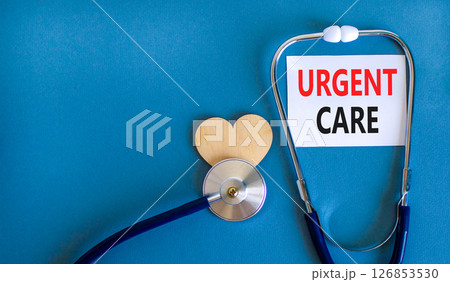 Urgent care symbol. Concept words Urgent care on beautiful white card. Wooden heart and stethoscope. Beautiful blue background. Medical healthy lifestyle urgent care concept. 126853530
