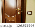 Partially Open Wooden Door with Gold Handle 126853596