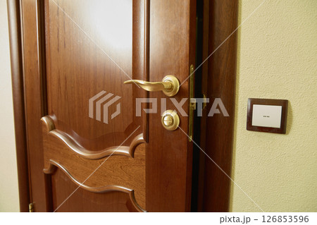 Partially Open Wooden Door with Gold Handle 126853596