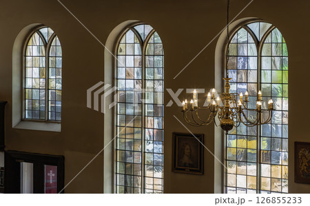 A stunning view of Chandelier hanging from the ceiling and Large stained glass windows in the background. A stunning view of Chandelier hanging from the ceiling and Large stained glass windows in the background. 126855233
