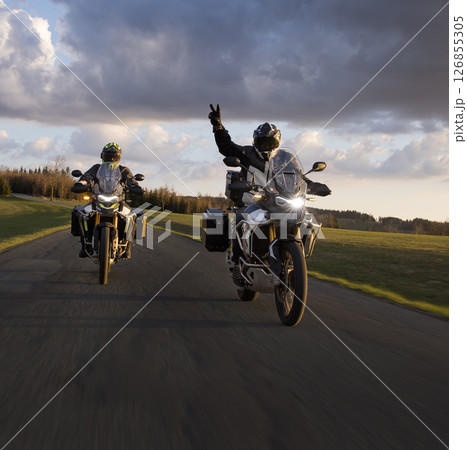 Driver riding motorcycle on empty road during sunset, spring mountains 126855305