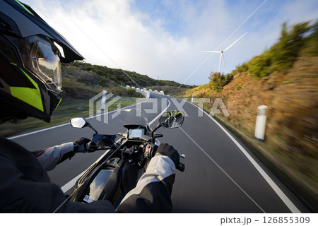 Driver riding motorcycle on empty asphalt road, handlebars view , spring mountains 126855309