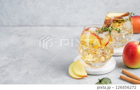 Two glasses of chilled apple cocktail or cider with ice, garnished with cinnamon and thyme Two glasses of chilled apple cocktail or cider with ice, garnished with cinnamon and thyme 126856272