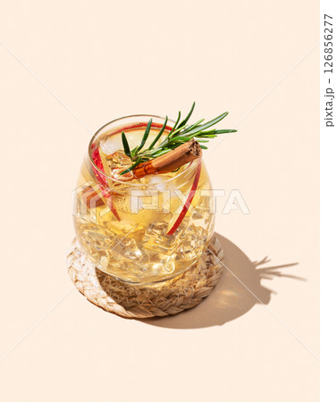 Apple cocktail or cider in a glass with ice, cinnamon and rosemary on a beige background 126856277