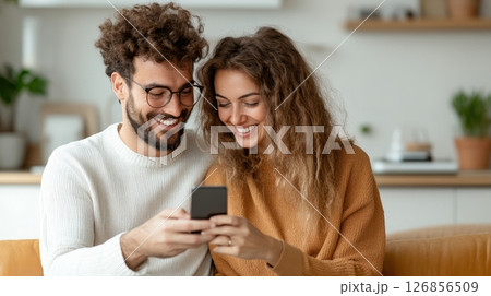 Affectionate Couple Sharing Smartphone Moment in Cozy Kitchen   Young Caucasian Man and Woman Smiling Embracing and Enjoying Digital Connection in Intimate Warm Domestic Setting 126856509