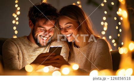 Cheerful couple embracing intimately while surrounded by warm festive lighting and cozy atmosphere  Affectionate loving partners sharing a romantic moment indoors 126856518