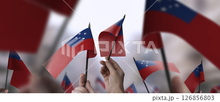 Samoa flags in their hands on a blurred urban background 126856803