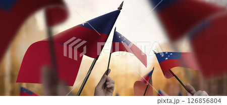 Samoa flags in their hands on a blurred urban background 126856804