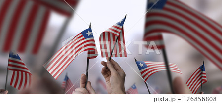 Liberia flags in their hands on a blurred urban background 126856808