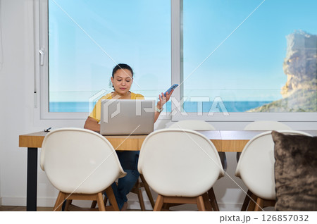 Confident Freelancer Working Remotely in a Scenic Home Office Setting Confident Freelancer Working Remotely in a Scenic Home Office Setting 126857032