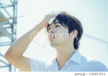 真夏の屋外作業中に汗を拭く作業員 真夏の屋外作業中に汗を拭く作業員 126857413