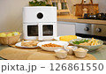 Modern air fryer cooking various dishes in kitchen: chicken, vegetables, and more 126861550