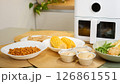 Air fryer cooking various dishes including corn, muffins, and vegetables 126861551