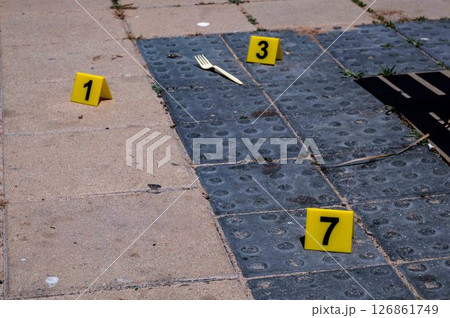 Three yellow crime scene markers on paving slabs Three yellow crime scene markers on paving slabs 126861749