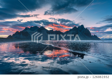 Sunset over volcanic Vestrahorn mountain reflecting on black sand beach in summer at Iceland Sunset over volcanic Vestrahorn mountain reflecting on black sand beach in summer at Iceland 126861932
