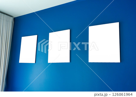 Three empty square canvas frames arranged on deep blue wall Three empty square canvas frames arranged on deep blue wall 126861964
