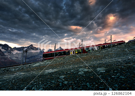 Cogwheel train of Gornergrat railway travelling thru swiss alps on hillside in the morning Cogwheel train of Gornergrat railway travelling thru swiss alps on hillside in the morning 126862104