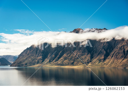 Rugged mountain range with foggy and blue sky in Lake Hawea lookout, New Zealand Rugged mountain range with foggy and blue sky in Lake Hawea lookout, New Zealand 126862153