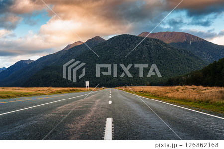 Straight Milford Road heading to mountain among meadow in the evening at New Zealand Straight Milford Road heading to mountain among meadow in the evening at New Zealand 126862168